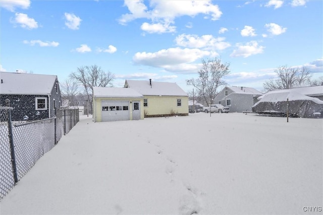 snow covered back of property with a garage and an outdoor structure