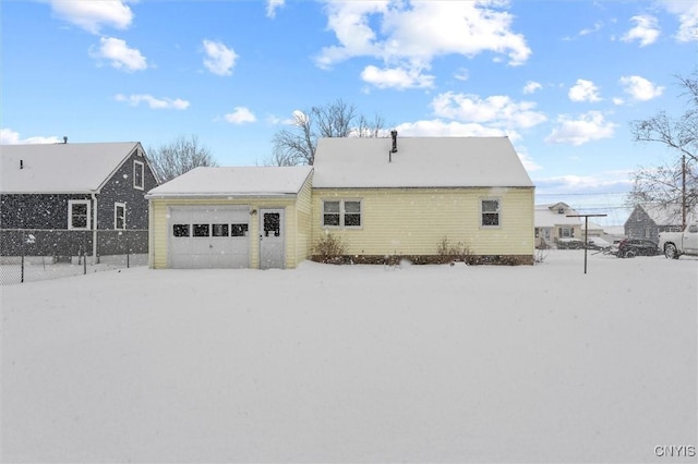 snow covered back of property featuring a garage