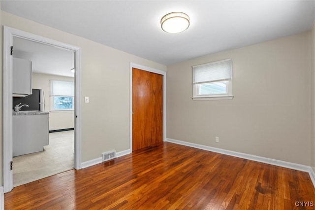 unfurnished bedroom with hardwood / wood-style flooring, sink, and a closet