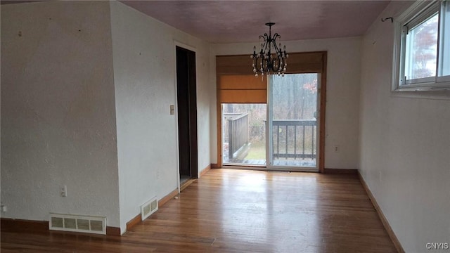 unfurnished dining area featuring a chandelier and hardwood / wood-style flooring