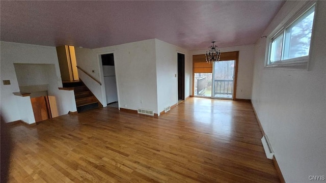 unfurnished living room with hardwood / wood-style flooring and an inviting chandelier