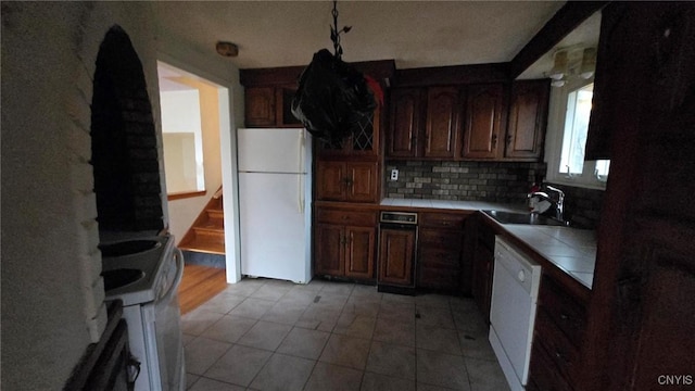 kitchen with tile countertops, decorative backsplash, white appliances, and sink