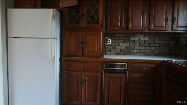 kitchen featuring tasteful backsplash, tile counters, and white refrigerator