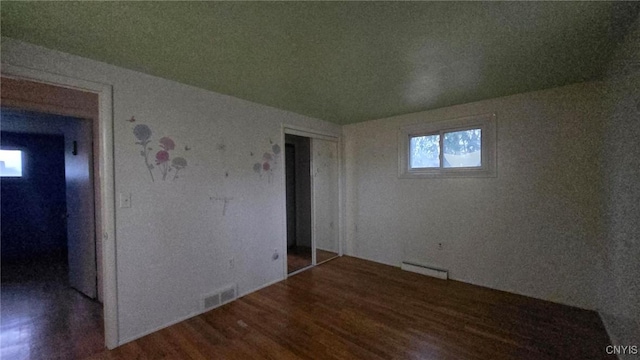 empty room with wood-type flooring and baseboard heating