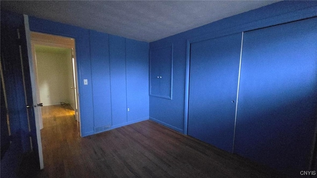 unfurnished bedroom with a closet and dark wood-type flooring