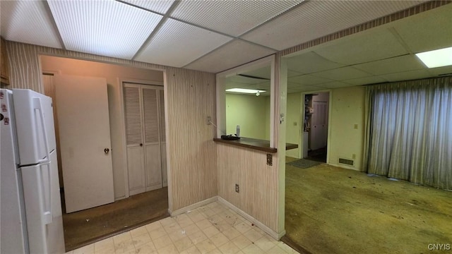 kitchen with wood walls, a paneled ceiling, and white refrigerator