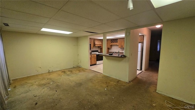 interior space with white appliances, a kitchen bar, a paneled ceiling, and kitchen peninsula