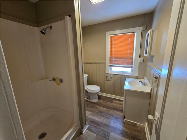 bathroom with hardwood / wood-style floors, vanity, toilet, and walk in shower