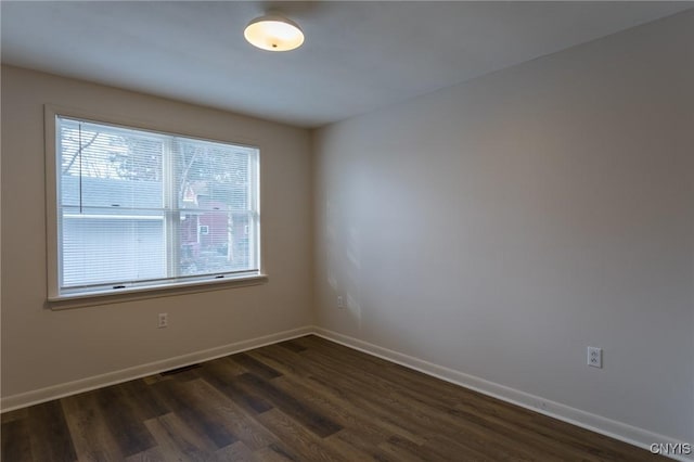 empty room with a wealth of natural light and dark hardwood / wood-style floors