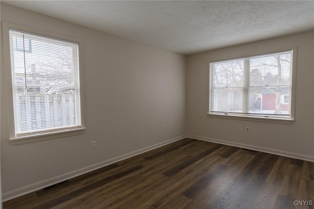 spare room featuring dark wood-type flooring and a textured ceiling