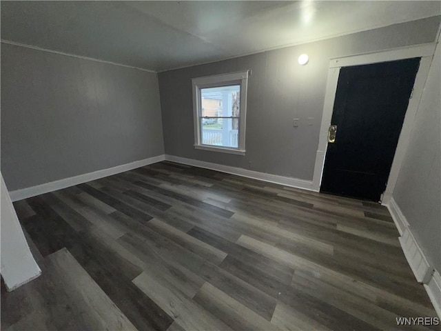 interior space with dark wood-type flooring, ornamental molding, and baseboards