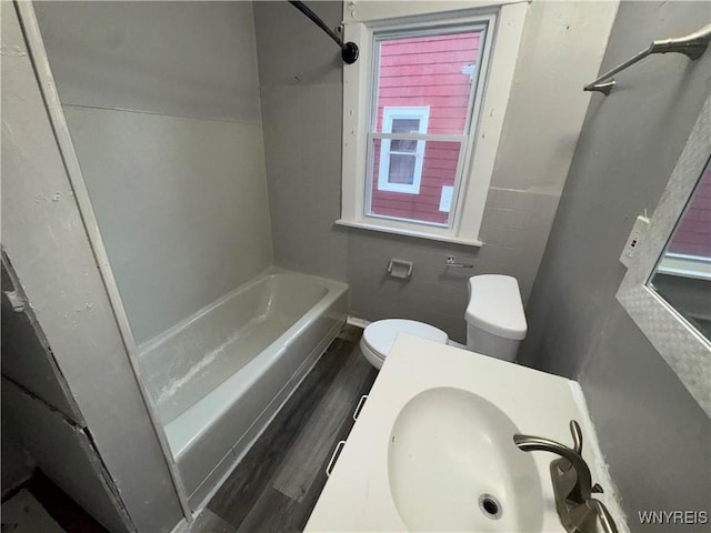 full bath with a sink, shower / bathing tub combination, toilet, and wood finished floors