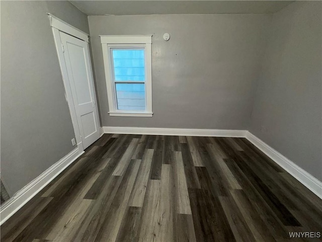 empty room with dark wood-style floors and baseboards