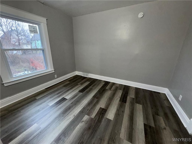 unfurnished room with baseboards and dark wood-type flooring