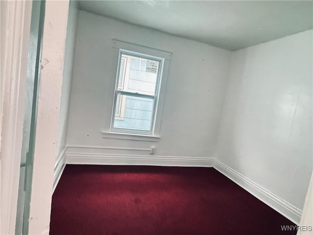 empty room with dark carpet and baseboards