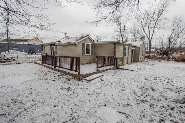 snow covered rear of property with a wooden deck