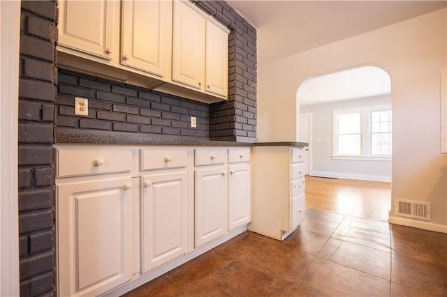 kitchen featuring white cabinets, decorative backsplash, and dark tile patterned floors