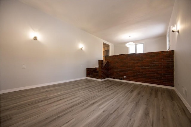 empty room with dark hardwood / wood-style floors and brick wall