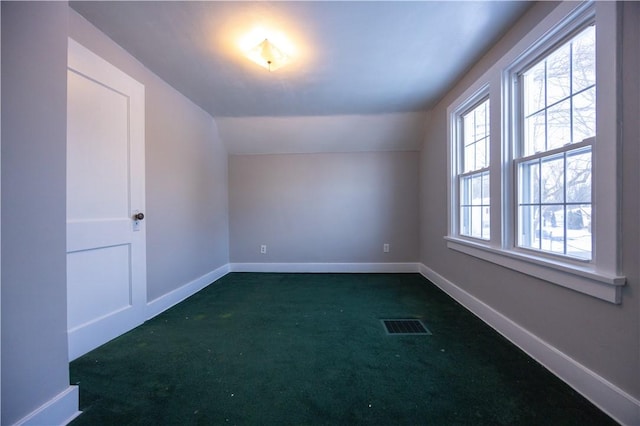 additional living space with dark carpet and vaulted ceiling