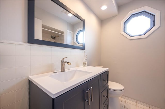 bathroom featuring tasteful backsplash, tile patterned floors, toilet, vanity, and tile walls