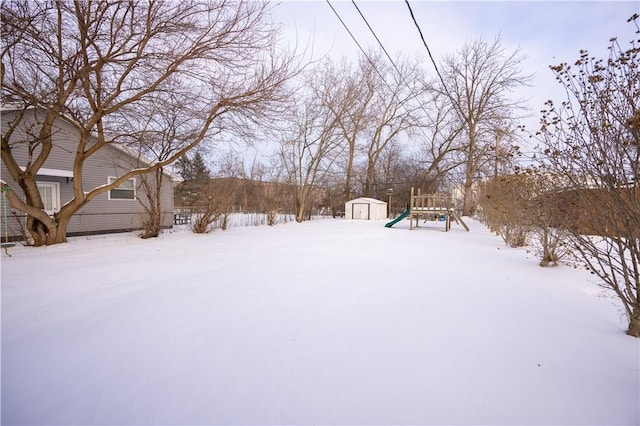 snowy yard featuring a shed