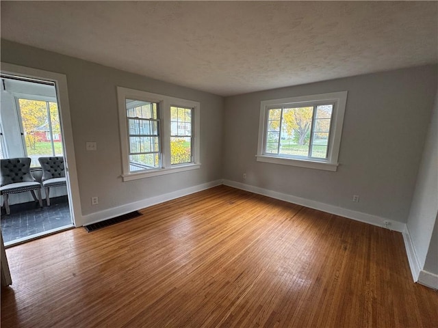 unfurnished room with wood-type flooring and a wealth of natural light