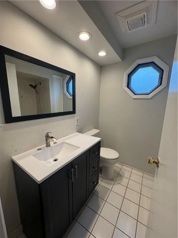 bathroom with toilet, vanity, and tile patterned floors