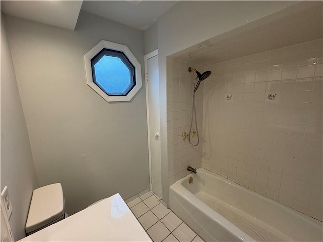 bathroom featuring tile patterned flooring, toilet, and tiled shower / bath