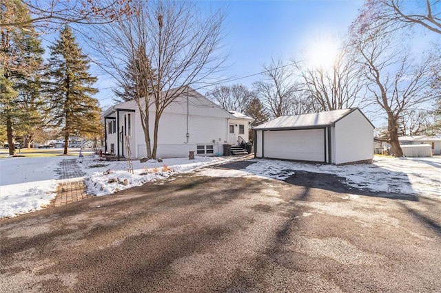 snow covered property featuring an outdoor structure and a garage