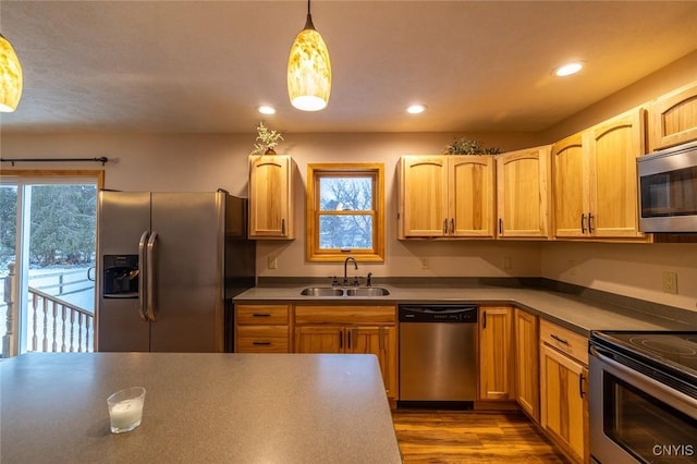 kitchen featuring sink, hanging light fixtures, light hardwood / wood-style flooring, light brown cabinetry, and appliances with stainless steel finishes