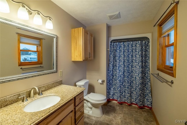 bathroom with a textured ceiling, vanity, toilet, and walk in shower