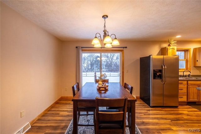 dining room featuring a chandelier, a textured ceiling, dark wood-type flooring, and sink