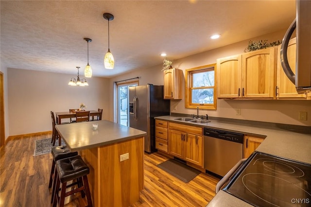 kitchen featuring a center island, an inviting chandelier, sink, appliances with stainless steel finishes, and decorative light fixtures