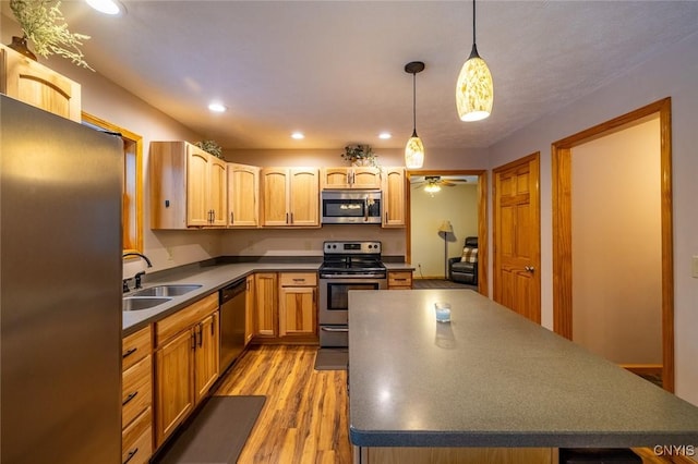 kitchen featuring light wood-type flooring, stainless steel appliances, ceiling fan, sink, and decorative light fixtures