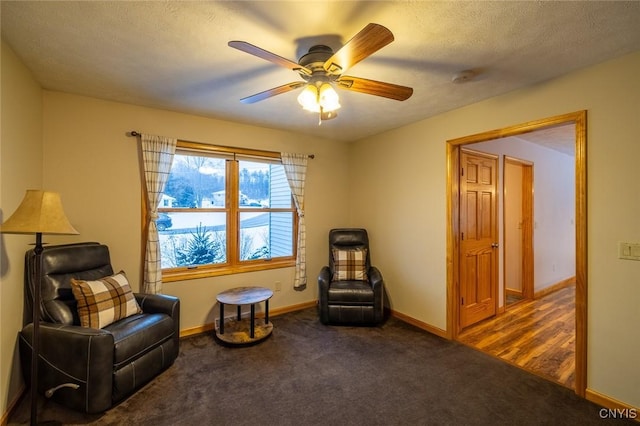 sitting room featuring ceiling fan, a textured ceiling, and dark colored carpet