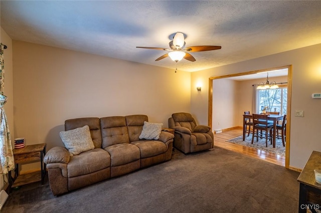 carpeted living room featuring ceiling fan with notable chandelier