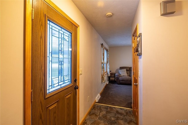 doorway to outside with plenty of natural light and a textured ceiling