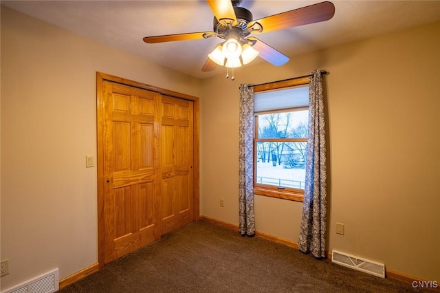 unfurnished bedroom with dark colored carpet, a closet, and ceiling fan