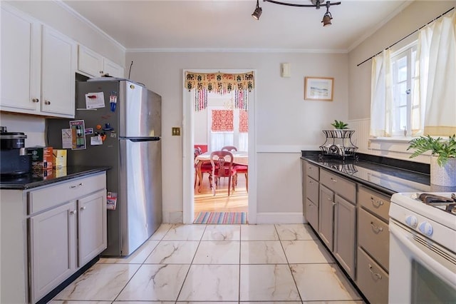 kitchen with white cabinets, ornamental molding, white stove, and stainless steel refrigerator