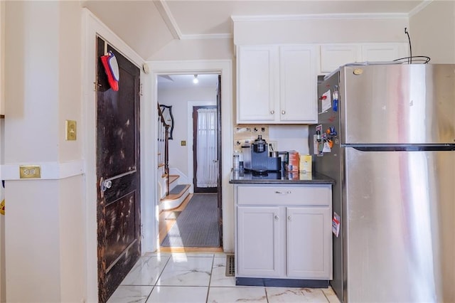 kitchen featuring white cabinets, stainless steel refrigerator, and ornamental molding