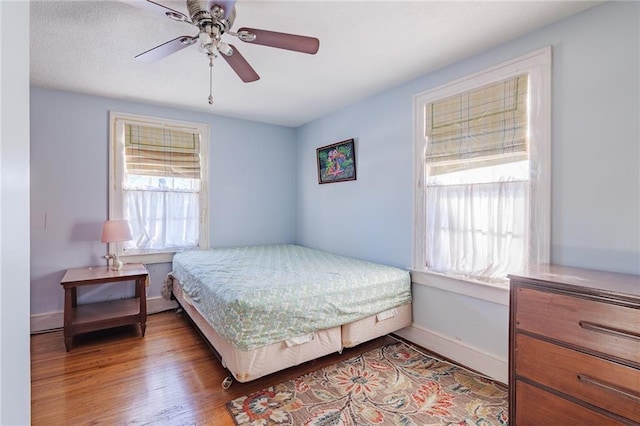 bedroom with multiple windows, ceiling fan, and wood-type flooring