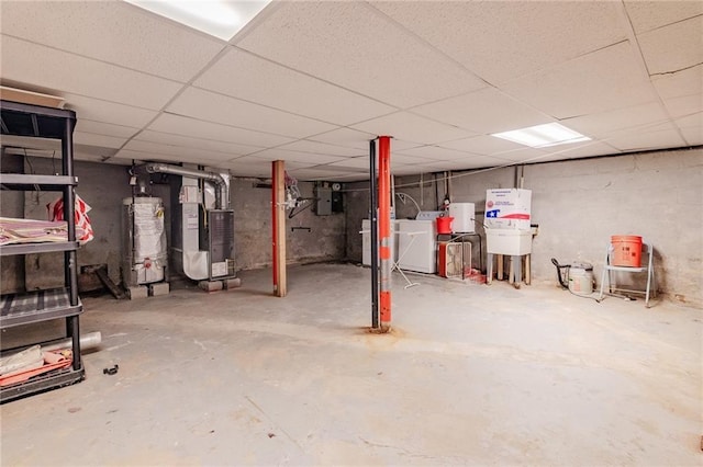 basement featuring a paneled ceiling, heating unit, washer and clothes dryer, water heater, and electric panel