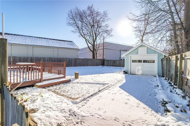 snowy yard featuring a deck, an outdoor structure, and a garage