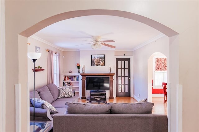 living room with ceiling fan, light wood-type flooring, plenty of natural light, and ornamental molding