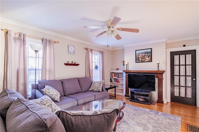 living room featuring ceiling fan, light wood-type flooring, and ornamental molding