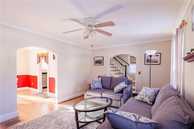 living room with ceiling fan, light wood-type flooring, crown molding, and a wealth of natural light