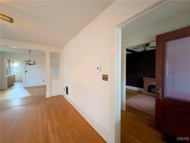 hallway with hardwood / wood-style flooring and an inviting chandelier