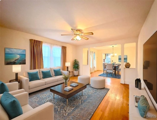 living room with ceiling fan with notable chandelier and hardwood / wood-style flooring