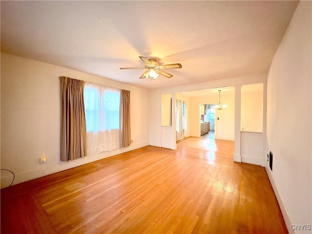 spare room with hardwood / wood-style floors and ceiling fan with notable chandelier