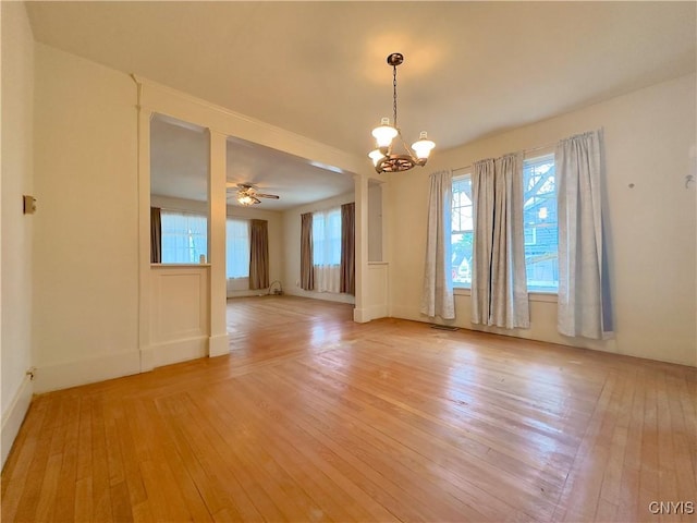 unfurnished room featuring ceiling fan with notable chandelier and light wood-type flooring